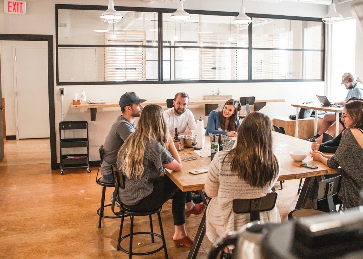 Colleagues in conversation around a table in an open office