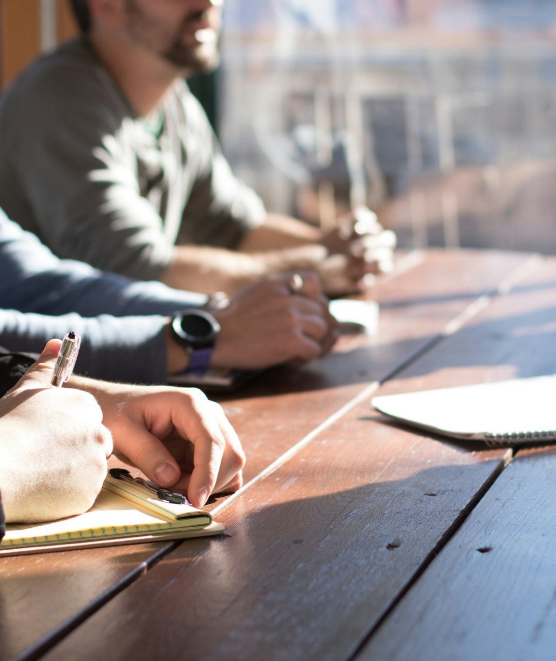 Leaders taking notes around a wooden table in warm daylight